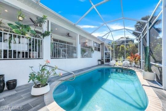 View of swimming pool with glass enclosure and ceiling fan