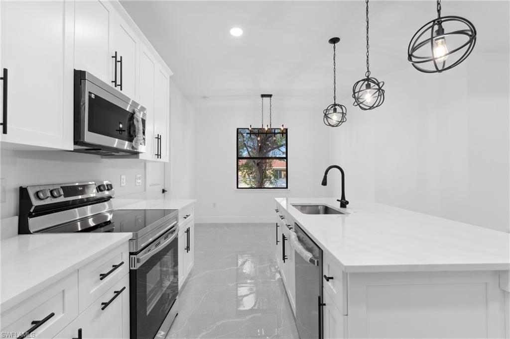 Kitchen featuring white cabinets, appliances with stainless steel finishes, and pendant lighting