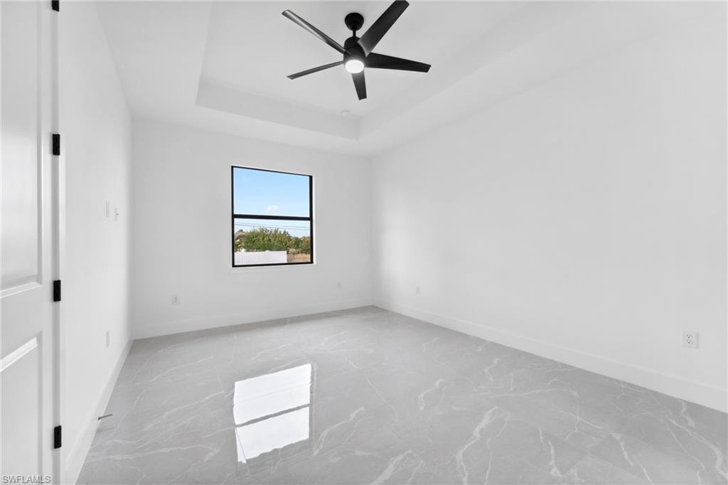 Spare room with a tray ceiling and ceiling fan