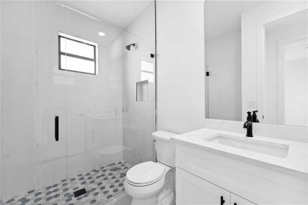 Bathroom featuring tile patterned flooring, vanity, a shower with shower door, and toilet