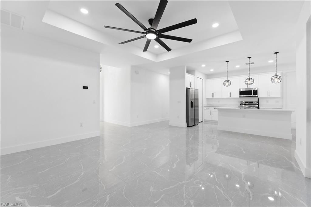 Unfurnished living room featuring a tray ceiling and ceiling fan