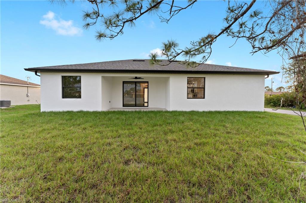 Rear view of house with a lawn and central AC unit