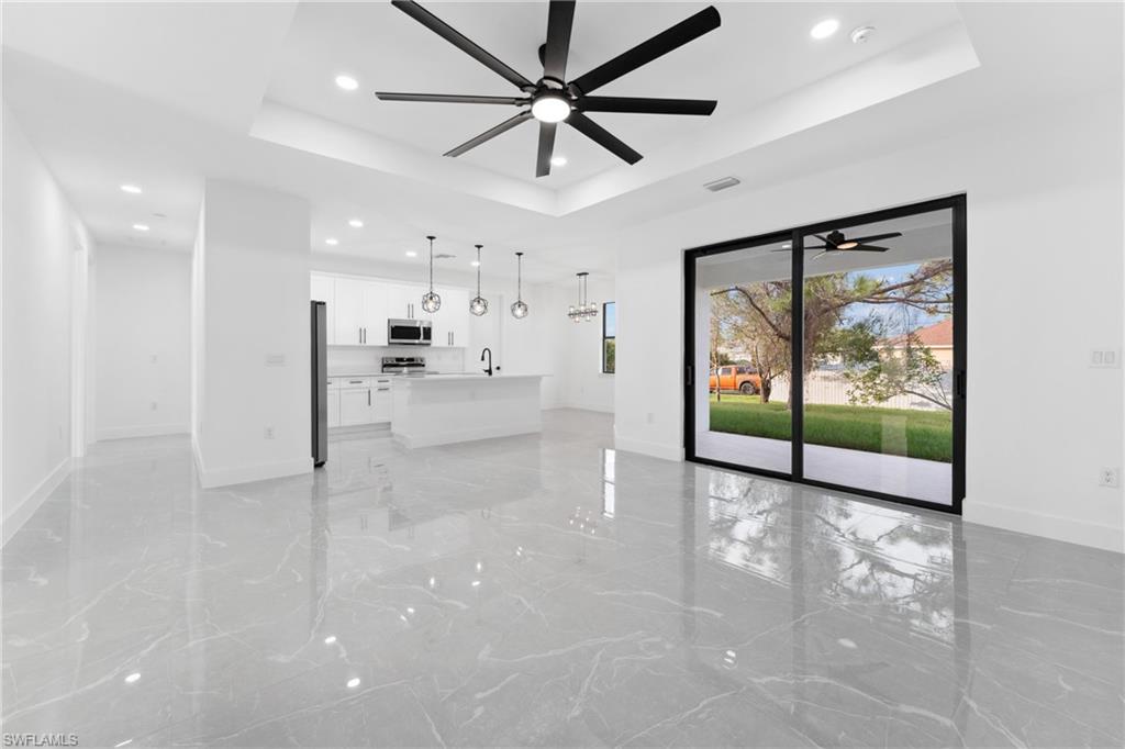 Unfurnished living room with a raised ceiling, ceiling fan, and sink