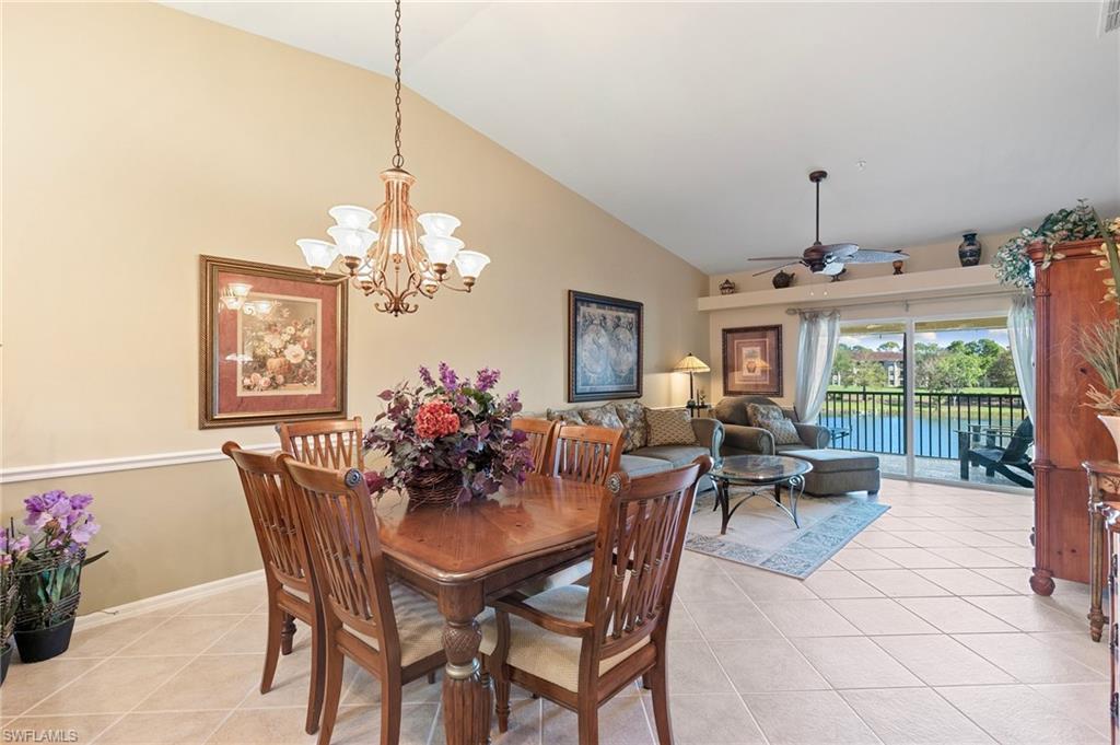 Tiled dining room featuring high vaulted ceiling and ceiling fan with chandelier open to the living room
