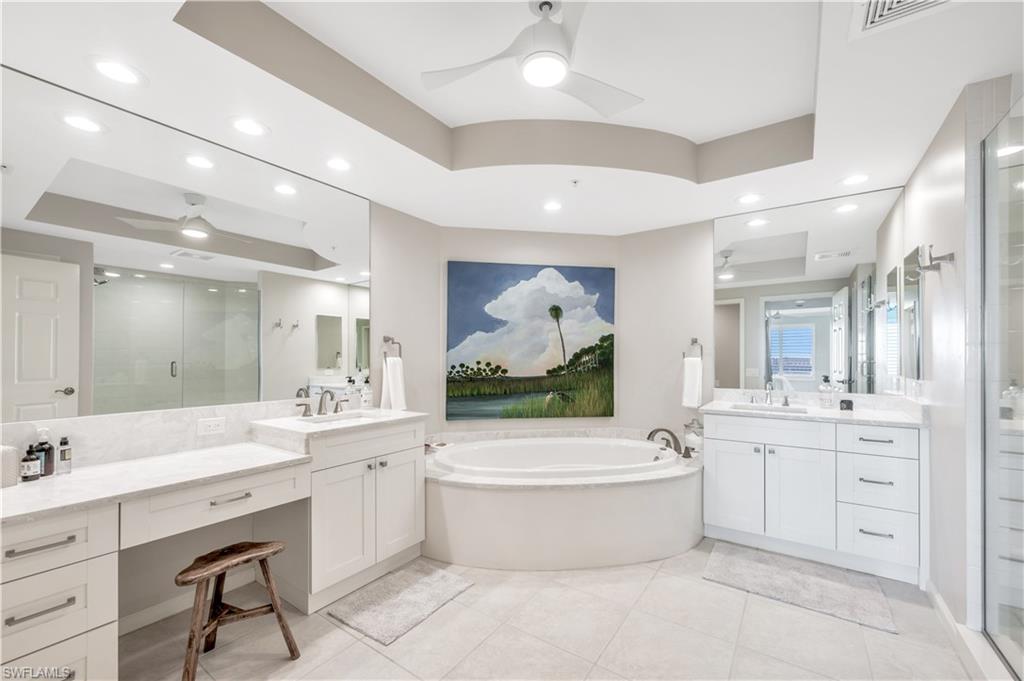 Bathroom featuring ceiling fan, a raised ceiling, tile patterned floors, shower with separate bathtub, and vanity