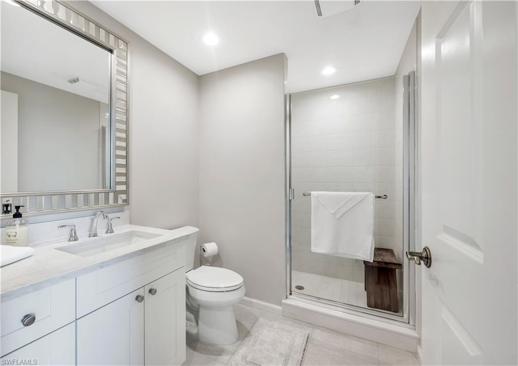 Bathroom with toilet, vanity, tile patterned floors, and a shower with shower door