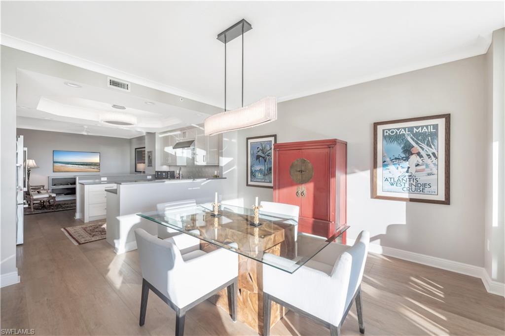 Dining area with a tray ceiling, crown molding, and light hardwood / wood-style floors