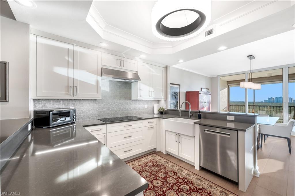 Kitchen with kitchen peninsula, dishwasher, white cabinets, and sink