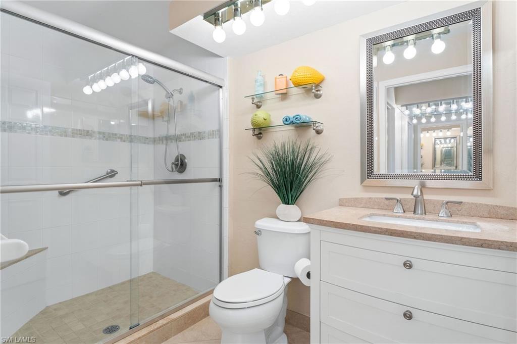 Bathroom with tile patterned floors, a shower with door, vanity, and toilet