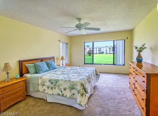 Carpeted bedroom featuring ceiling fan and a textured ceiling