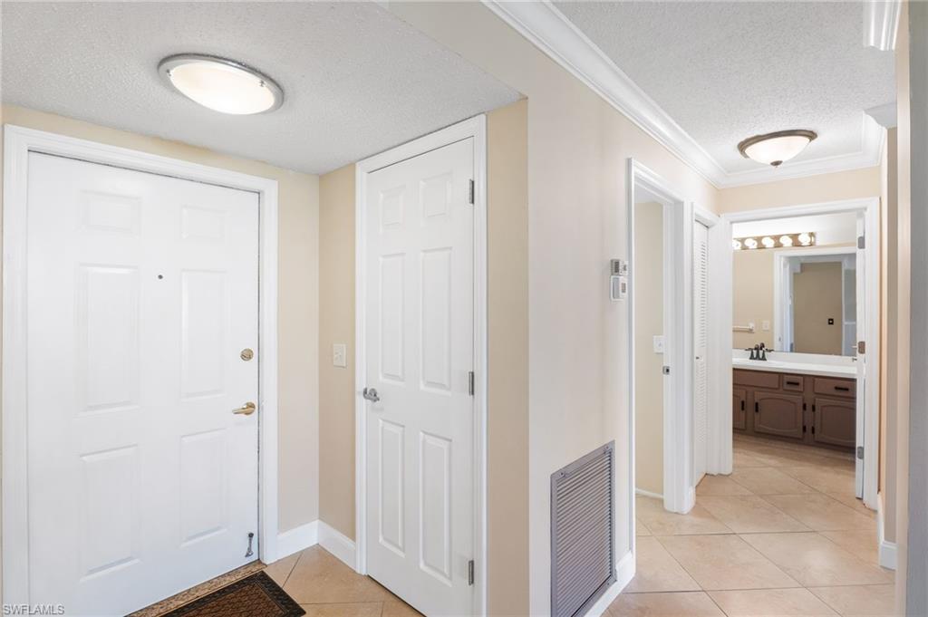Tiled entrance foyer featuring sink, crown molding, and a textured ceiling