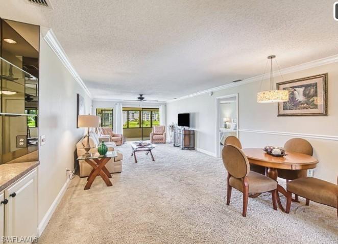 Dining area featuring crown molding, a textured ceiling, light colored carpet, and ceiling fan