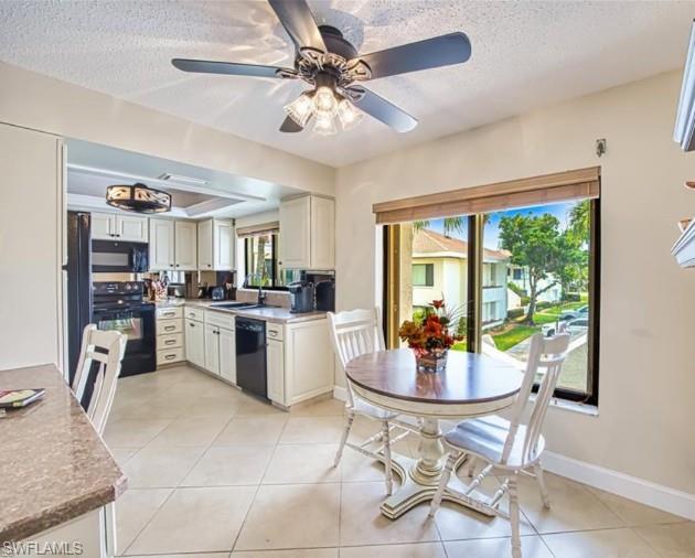 Kitchen featuring black appliances, ceiling fan, a textured ceiling, light tile patterned floors, and white cabinets