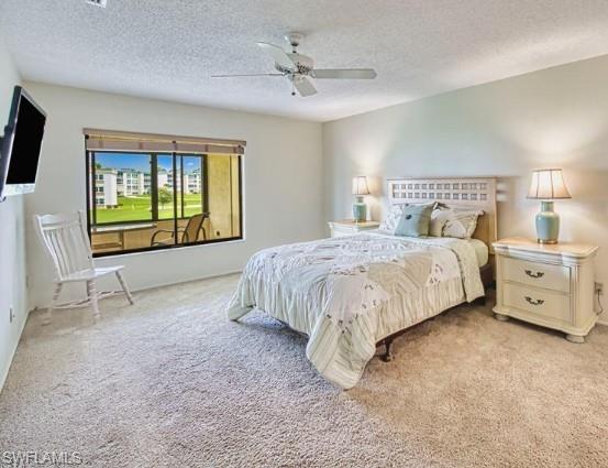 Bedroom with light colored carpet, a textured ceiling, and a ceiling fan