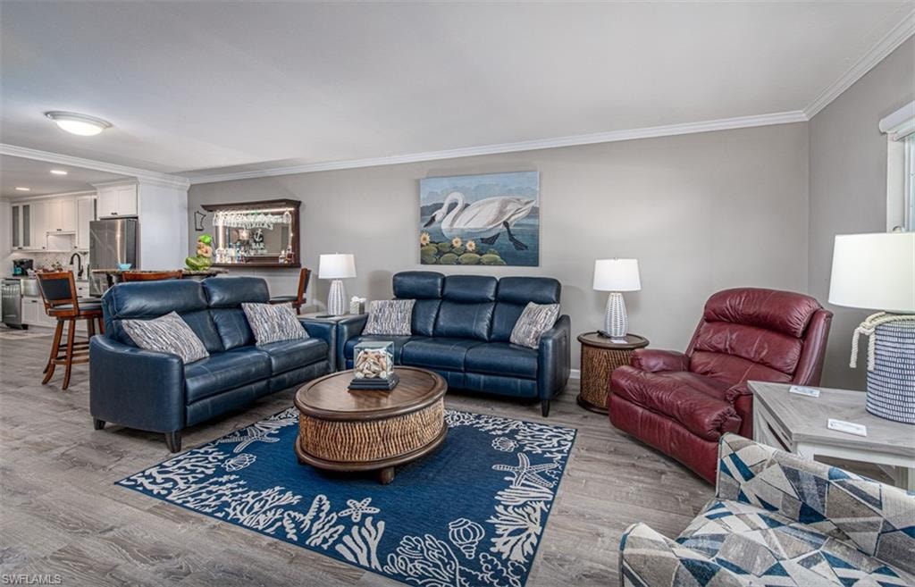 Living room featuring light wood-type flooring and crown molding