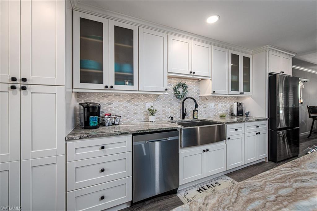Kitchen with light stone countertops, dishwasher, and refrigerator