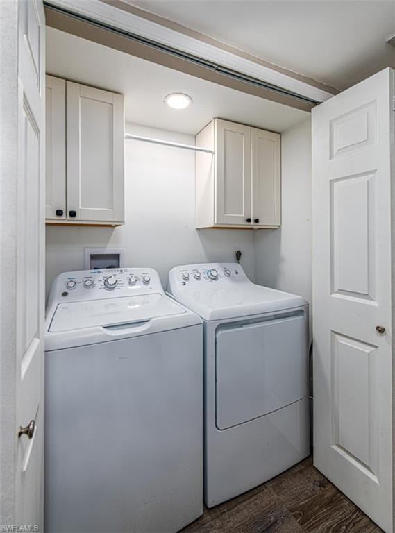 Laundry room with dark hardwood / wood-style floors, cabinets, and washing machine and clothes dryer