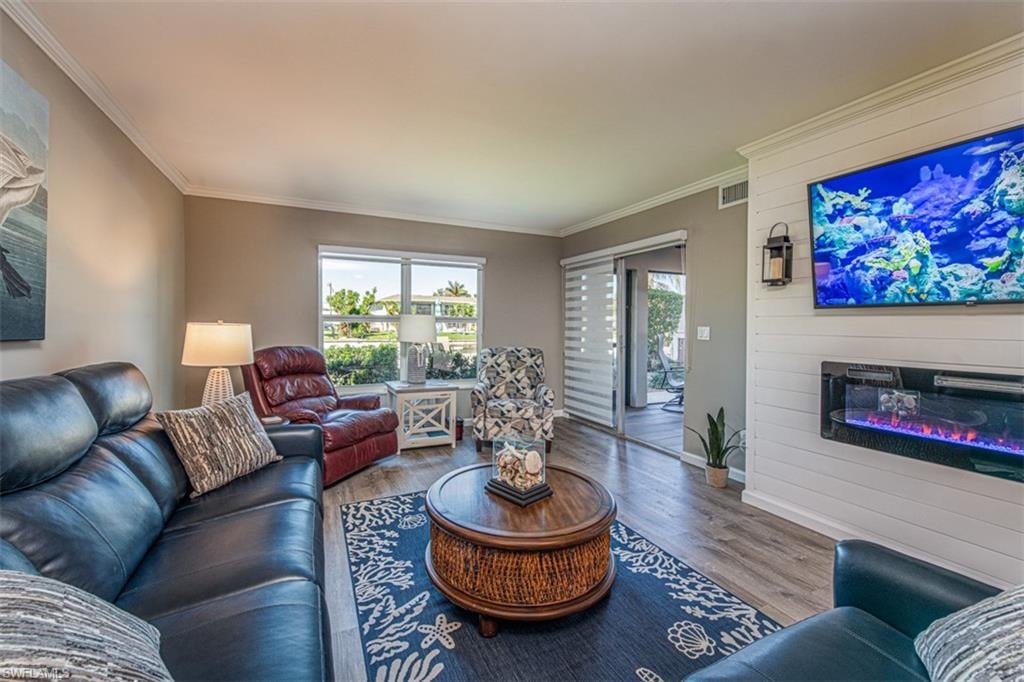 Living room featuring a large fireplace, hardwood / wood-style flooring, and crown molding