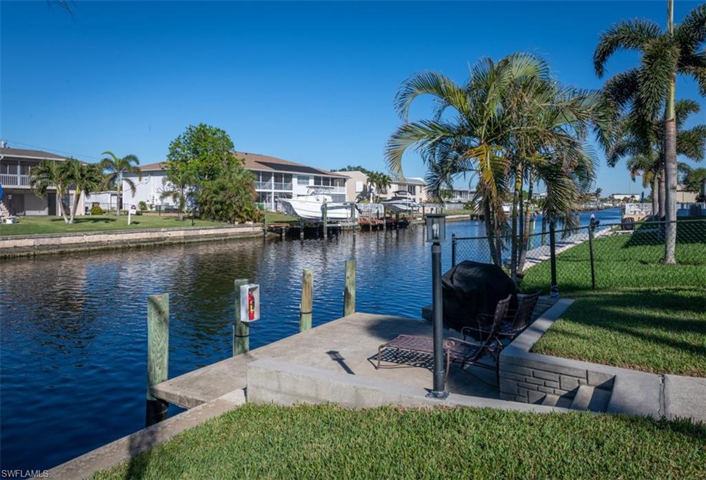 View of dock featuring a lawn and a water view