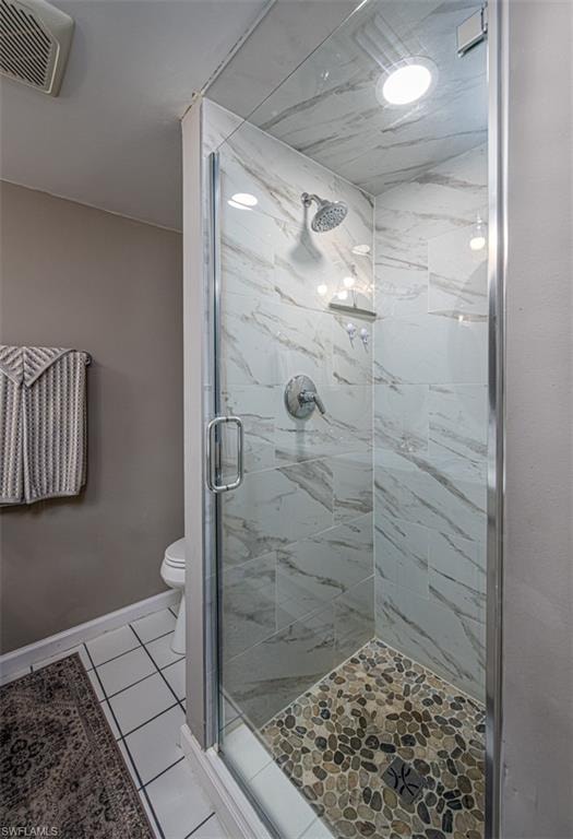 Bathroom with toilet, tile patterned floors, and an enclosed shower