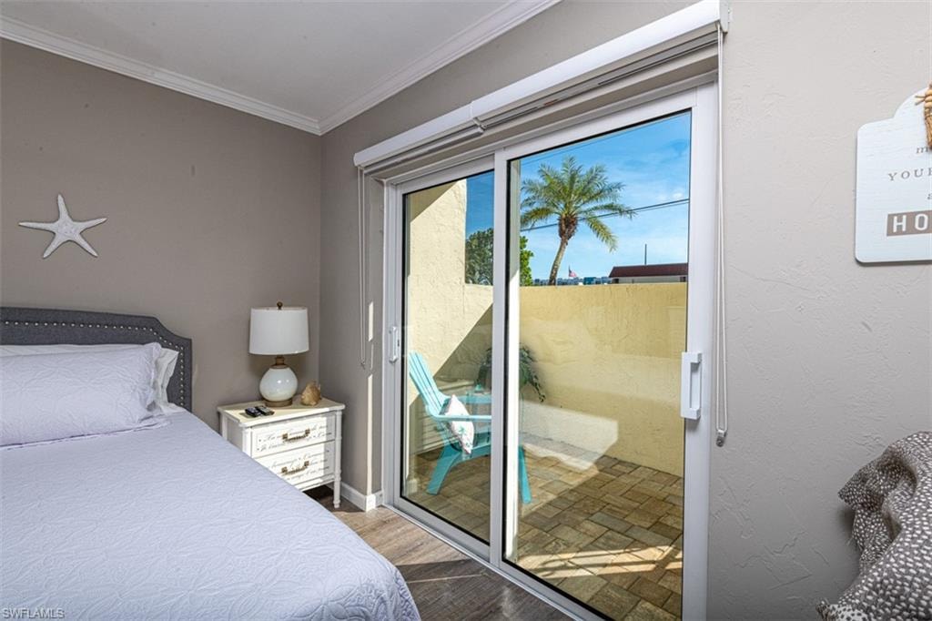 Bedroom featuring access to exterior, light hardwood / wood-style flooring, and ornamental molding