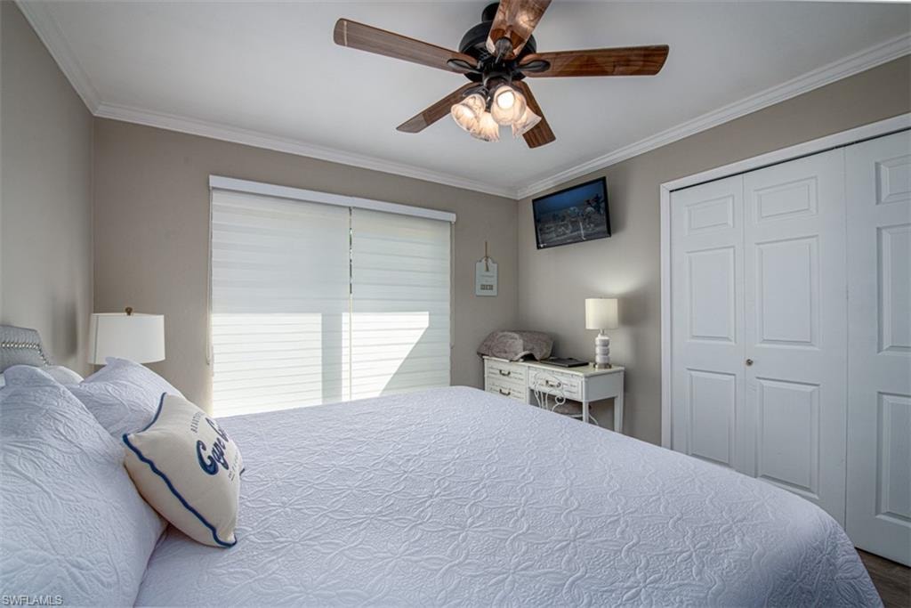 Bedroom featuring wood-type flooring, a closet, ceiling fan, and ornamental molding
