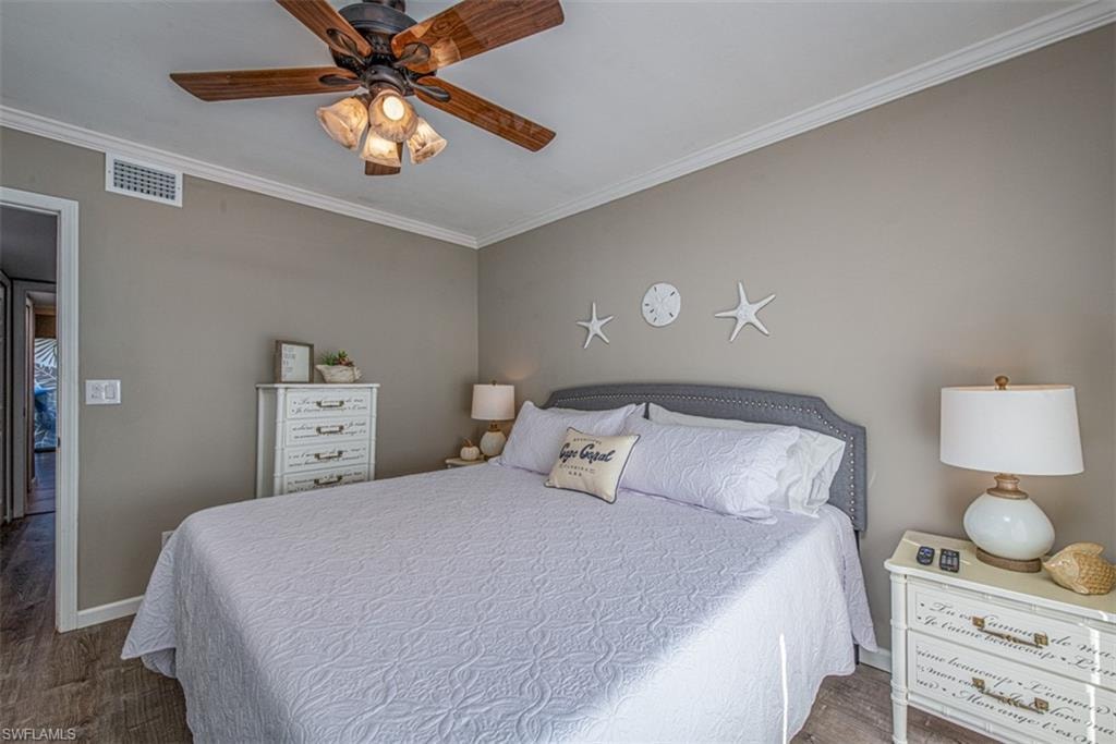 Bedroom featuring ceiling fan, dark wood-type flooring, and ornamental molding