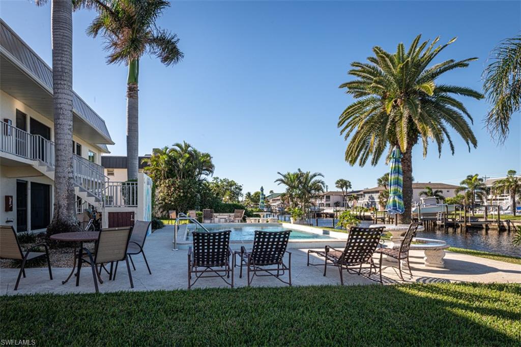 View of swimming pool featuring a lawn, a water view, and a patio