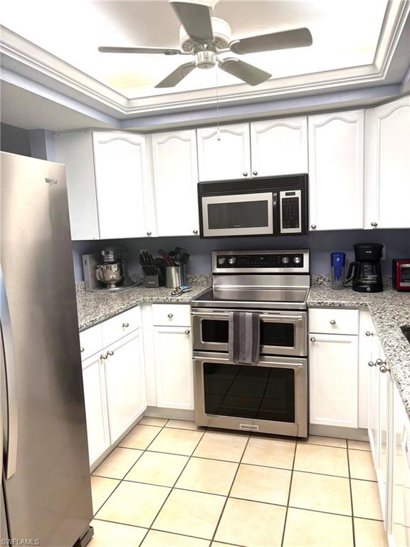 Kitchen featuring light tile patterned flooring, white cabinetry, and stainless steel appliances