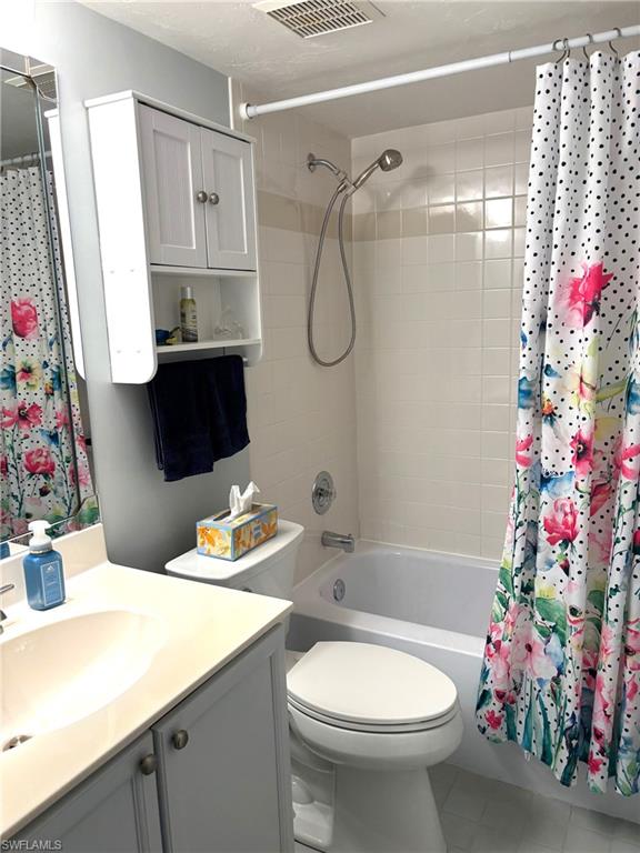 Full bathroom featuring tile patterned floors, shower / bath combo with shower curtain, vanity, and toilet
