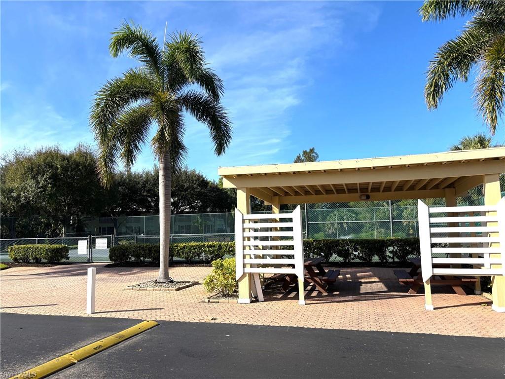 View of vehicle parking featuring tennis court
