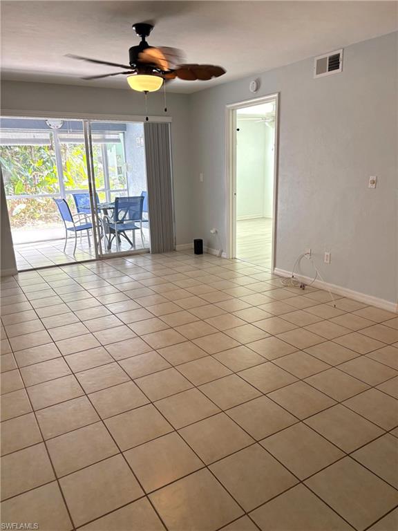 Empty room with ceiling fan and light tile patterned flooring