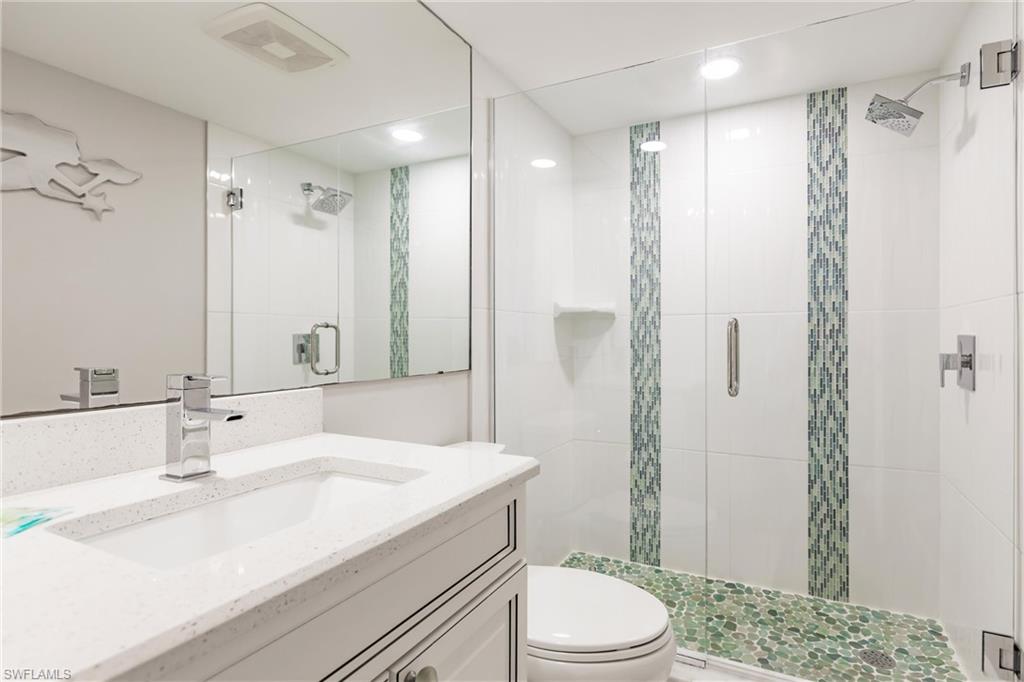 Bathroom featuring vanity, a shower with shower door, and toilet