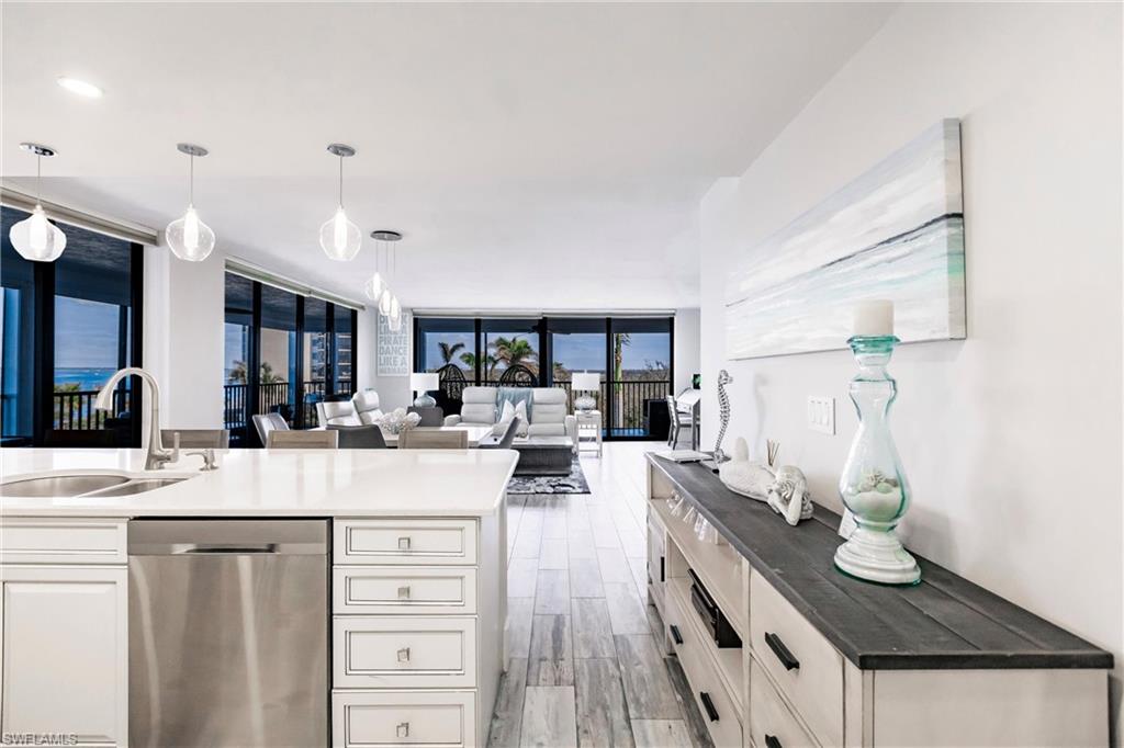 Kitchen with dishwasher, expansive windows, decorative light fixtures, and sink
