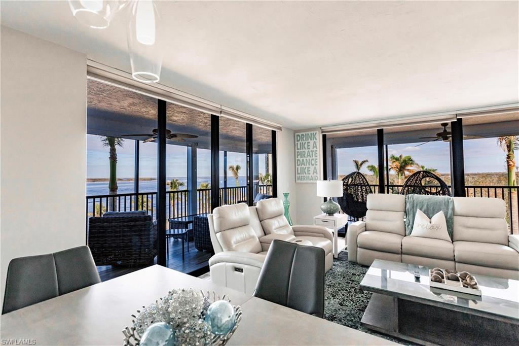 Living room featuring hardwood / wood-style floors, a water view, a wall of windows, and a healthy amount of sunlight