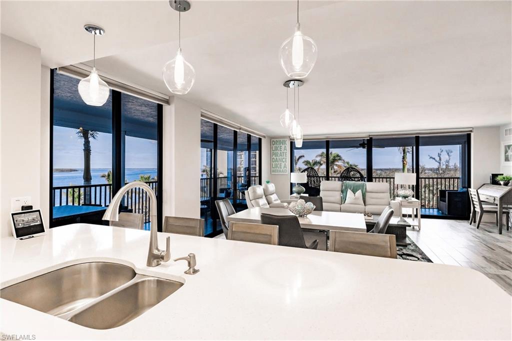 Kitchen featuring expansive windows, a water view, sink, and hanging light fixtures