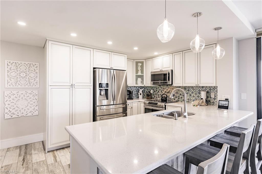 Kitchen with sink, a kitchen breakfast bar, kitchen peninsula, decorative light fixtures, and appliances with stainless steel finishes
