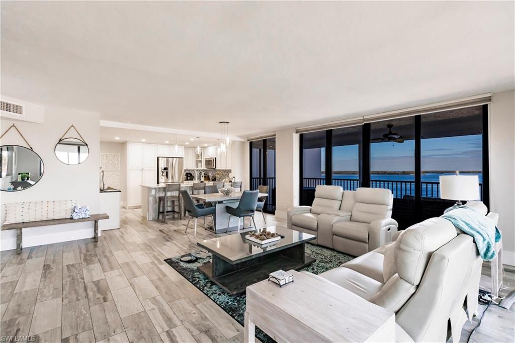 Living room featuring ceiling fan, a water view, a wall of windows, and light hardwood / wood-style flooring