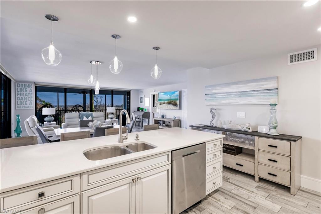 Kitchen featuring pendant lighting, stainless steel dishwasher, floor to ceiling windows, and sink