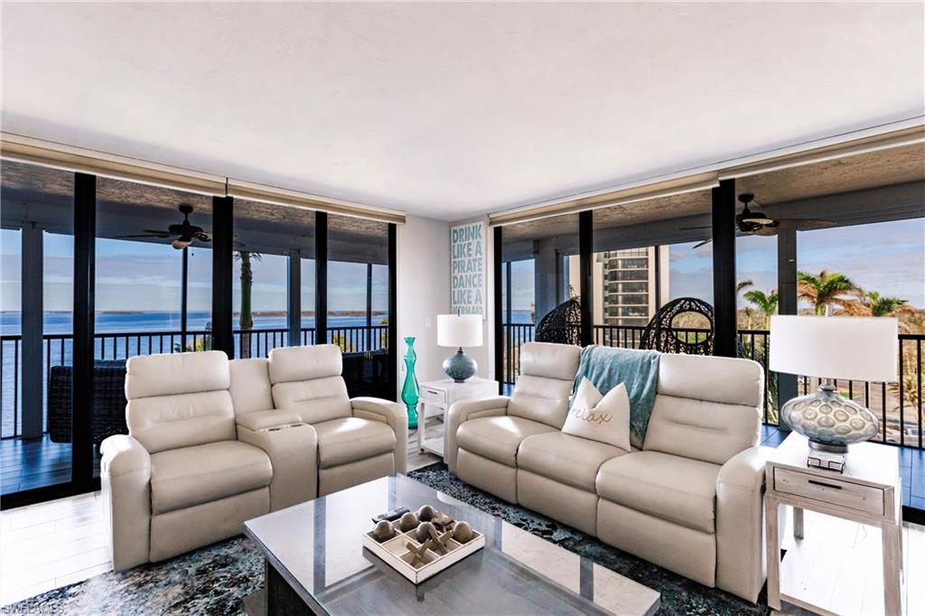 Living room featuring a water view, plenty of natural light, and a wall of windows