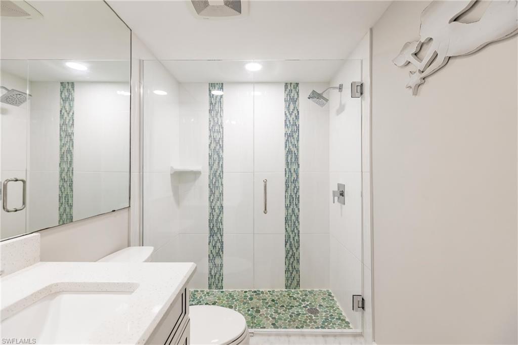 Bathroom with vanity, toilet, and a shower with shower door