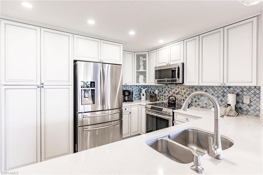 Kitchen featuring stainless steel appliances, white cabinetry, tasteful backsplash, and sink