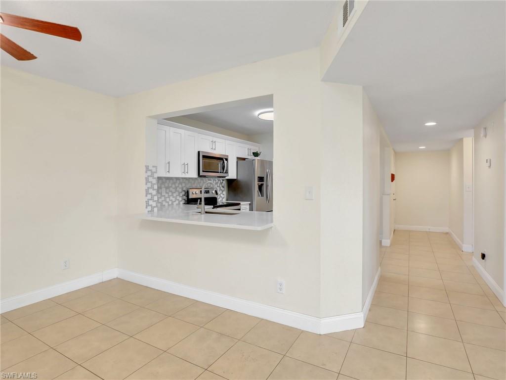 Kitchen with ceiling fan, tasteful backsplash, light tile patterned flooring, white cabinets, and appliances with stainless steel finishes