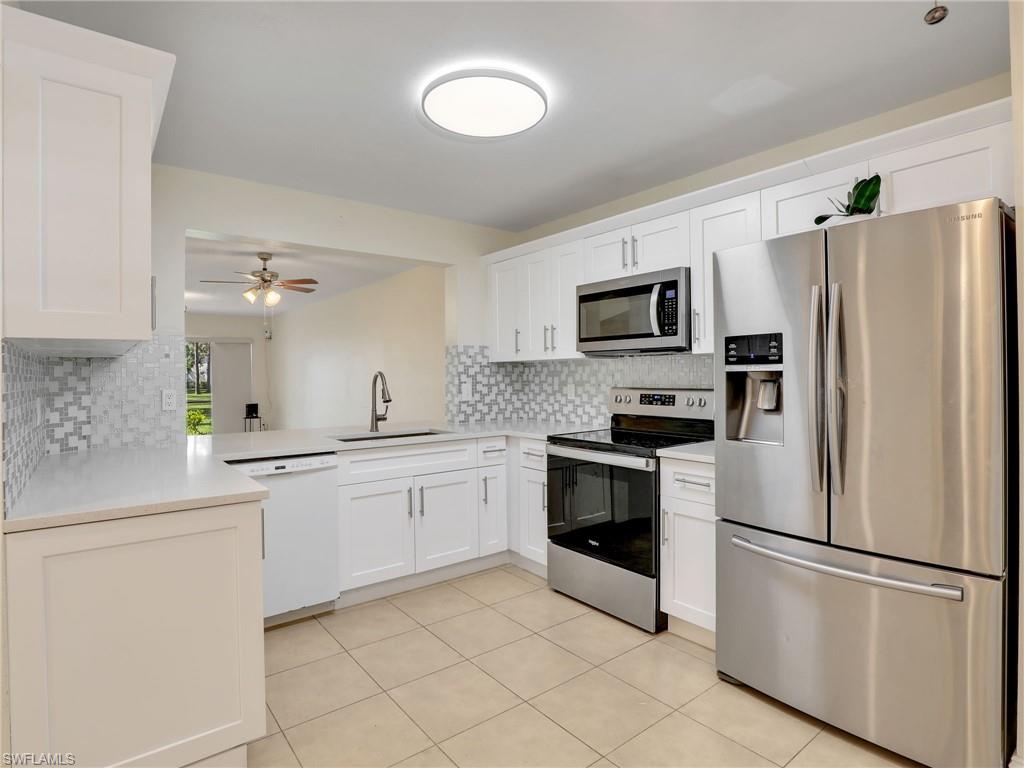 Kitchen featuring backsplash, stainless steel appliances, white cabinetry, and sink