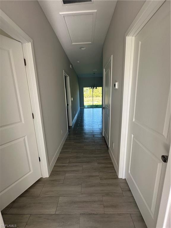 Hall featuring dark hardwood / wood-style flooring and a notable chandelier