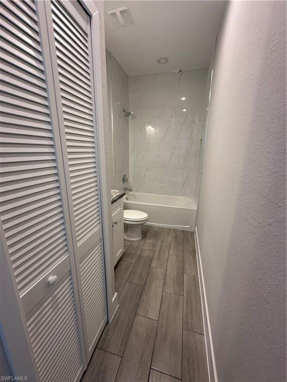 Full bathroom with tiled shower / bath, vanity, and toilet