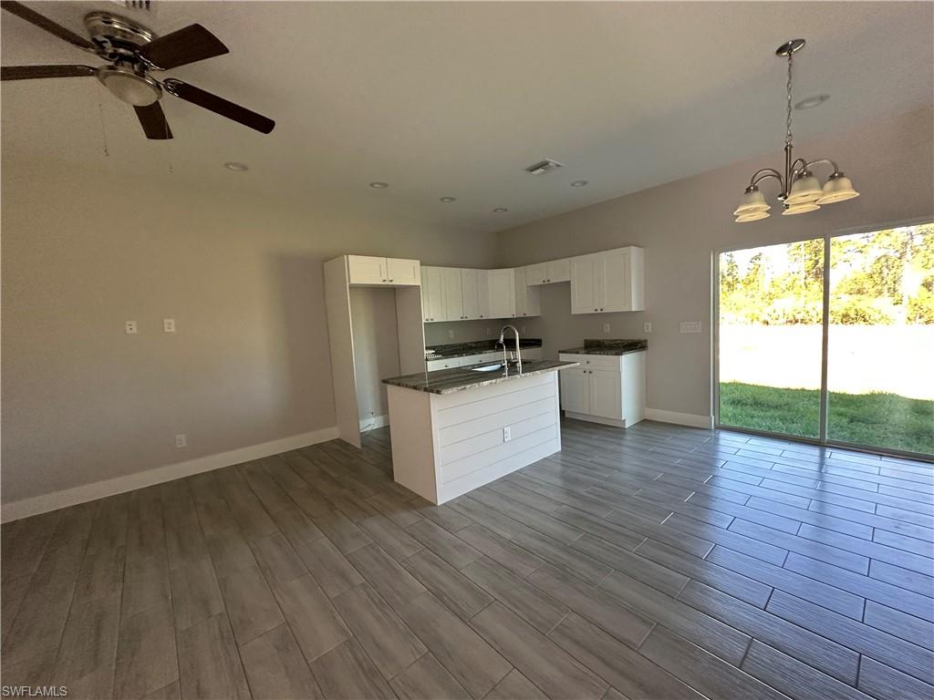 Kitchen featuring sink, hanging light fixtures, light hardwood / wood-style floors, a kitchen island with sink, and white cabinets