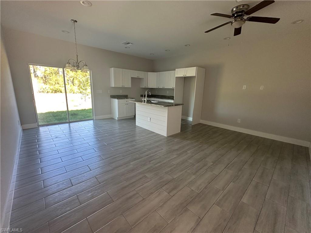 Kitchen featuring white cabinetry, sink, pendant lighting, a center island with sink, and light wood-type flooring