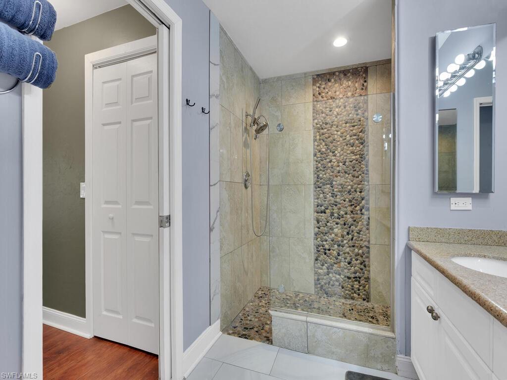 Bathroom featuring tiled shower, vanity, and hardwood / wood-style flooring