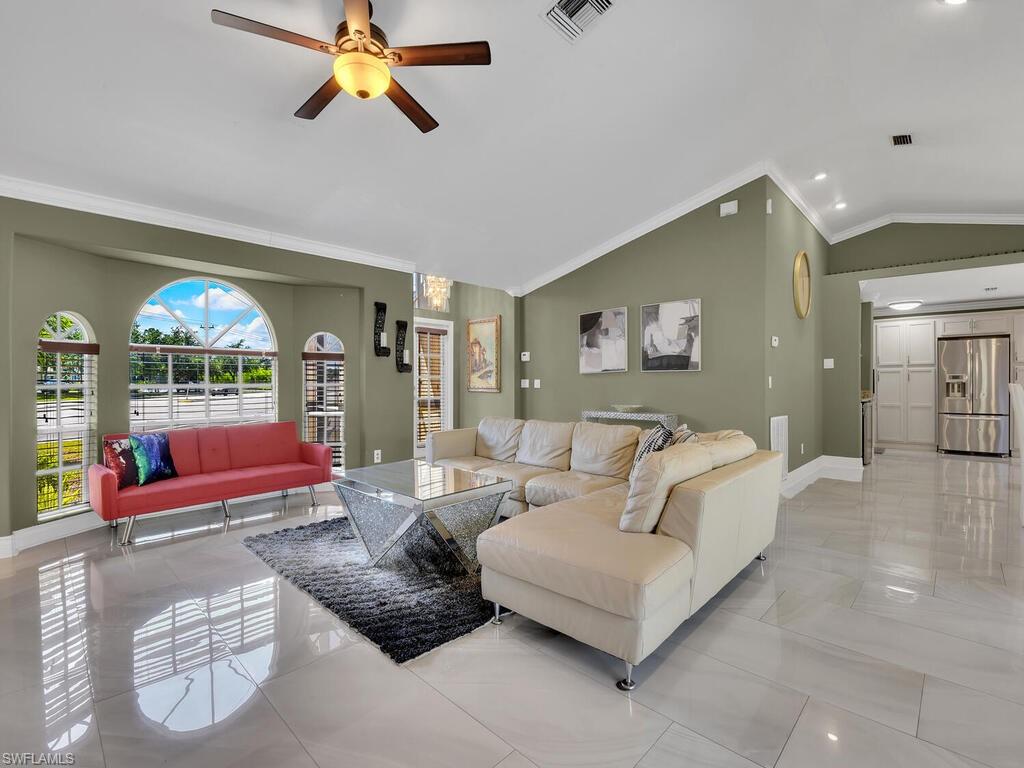 Living room with crown molding, ceiling fan, and vaulted ceiling